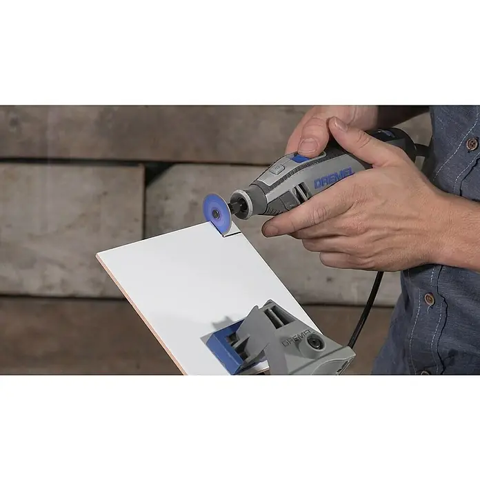 Dremel EZ SpeedClic Diamant-Trennscheibe Max Life SC545DM - Durchmesser: 38,1 mm, Passend für: Dremel Multifunktionswerkzeug - Nahaufnahme eines Dremel-Rotationswerkzeugs, das eine weiße Fliese schneidet, wobei der Fokus auf dem Werkzeug und seiner Präzision liegt.