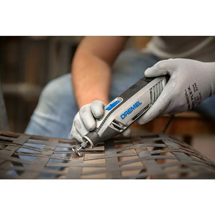 Dremel Multifunktionswerkzeug 4250-6/128 - 175 W, 5.000 U/min - 35.000 U/min - Ein Mann benutzt einen Dremel 4250 Multifunktionswerkzeug, um Metall zu bearbeiten, wobei er Handschuhe für zusätzlichen Schutz trägt.