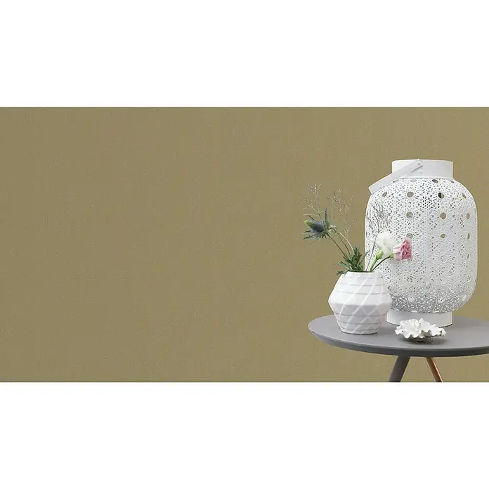 FREUNDIN Vliestapete - Gold, Uni, 10,05 x 0,53 m - Dekorative Nahaufnahme eines weißen, ornamentalen Windlichts und einer stilvollen Vase mit Blumen auf einem grauen Beistelltisch.