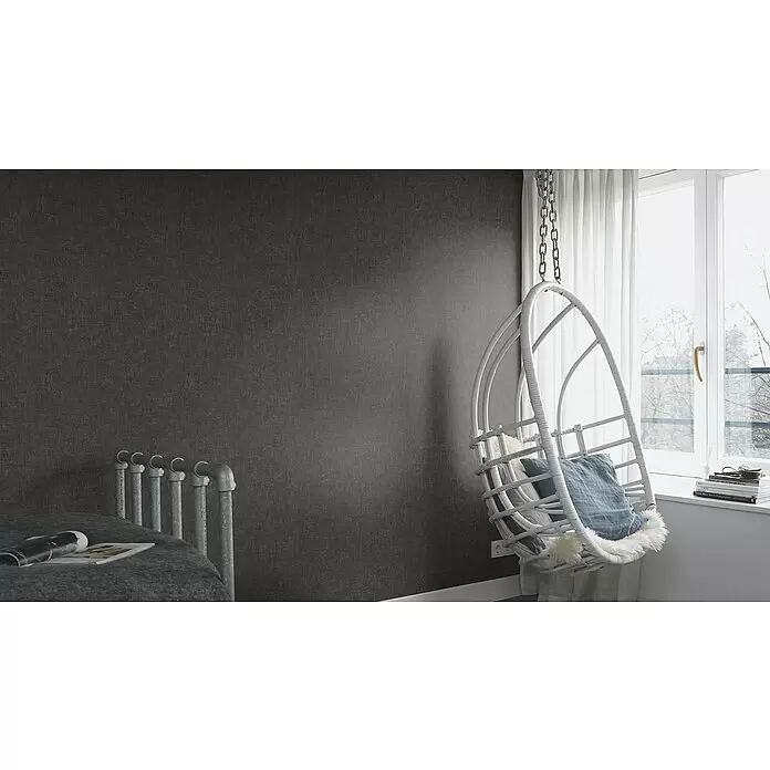 Rasch Factory 4 Vliestapete - Schwarz, Uni, 10,05 x 0,53 m - Dunkelgraue, texturierte Tapete an einer Wand in einem Zimmer, die ein modernes, industrielles Ambiente schafft.