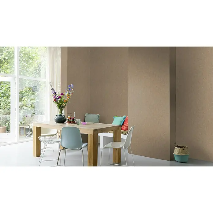 Rasch Factory 4 Vliestapete - Gold/Braun, Uni, 10,05 x 0,53 m - Esszimmer mit Holztisch, Stühlen, Blumen und Korb vor brauner Wand. Der Tisch dient als zentraler Punkt des Raumes mit natürlichem Licht.
