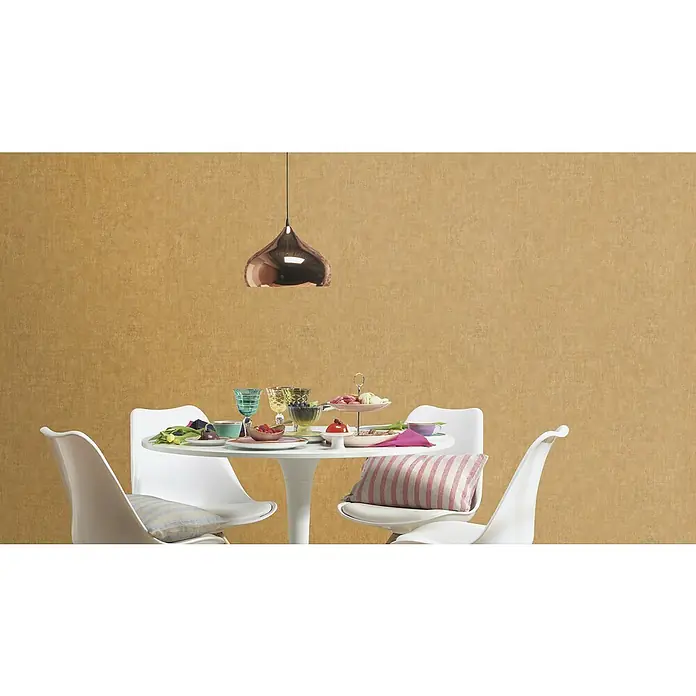 Rasch Factory 4 Vliestapete - Gold, Uni, 10,05 x 0,53 m - Esszimmertisch mit stilvollen Tulip Stühlen, Gläsern und dekorativem Geschirr unter einer modernen Kupferleuchte vor beiger Tapete.