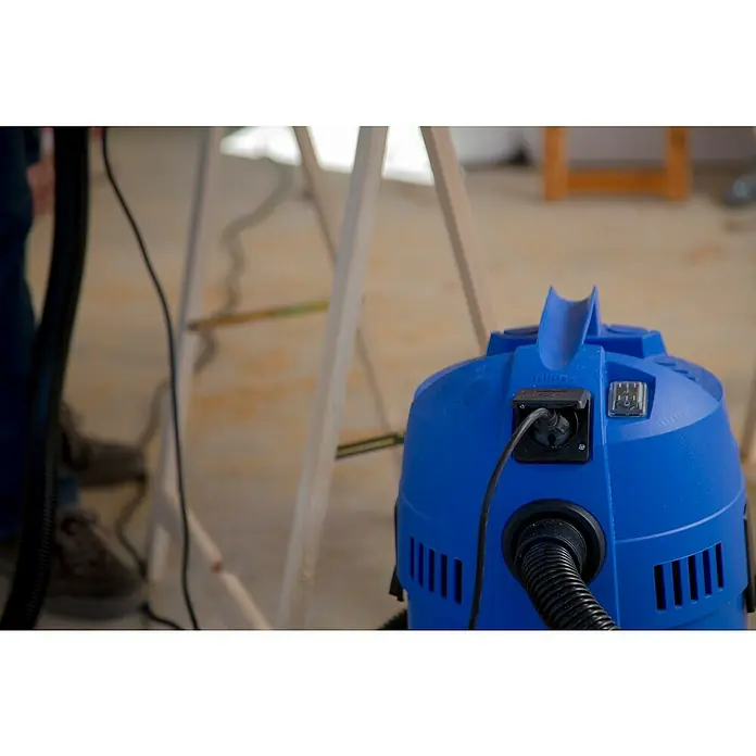 Nilfisk Elektro-Nass- & Trockensauger Buddy II 18 T - 1.200 W, Behältervolumen: 18 l, Mit Beutel - Nahaufnahme eines blauen Nilfisk Nass- und Trockensaugers mit Netzkabel und Stecker auf dem Boden.