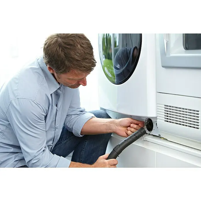 Nilfisk Elektro-Nass- & Trockensauger Multi II 22 - 1.200 W, Behältervolumen: 22 l - Ein Mann repariert eine weiße Waschmaschine mit einem Staubsaugerschlauch, um das Wasser zu entfernen. Er trägt ein hellblaues Hemd und Jeans.