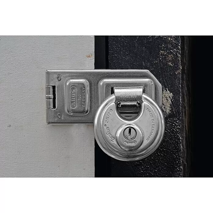 Abus Diskusschloss 26/70B - B x H: 70 x 70 mm, Bügelstärke: 10 mm, Edelstahl - Silbernes ABUS Diskus Vorhängeschloss 26/70 an ABUS Überfalle 140, sichert eine Tür.