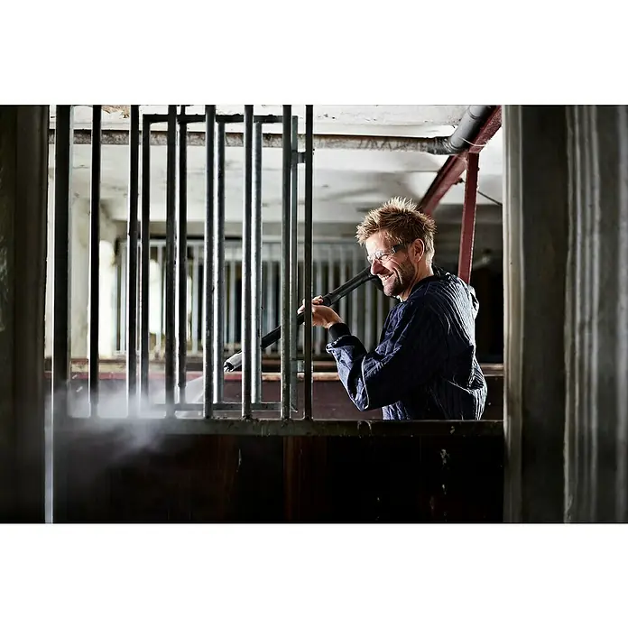 Nilfisk Hochdruckreiniger Premium 190-12 EU - 190 bar, 3.300 W, Fördermenge: 650 l/h - Ein Mann reinigt eine Stallung mit einem Hochdruckreiniger, wobei der Fokus auf dem Reinigungsprozess und der Ausrüstung liegt.