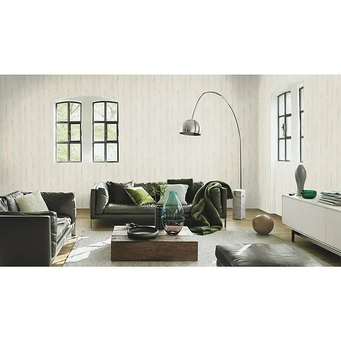 Rasch Vliestapete Holz I - Altweiß, Holzoptik, 10,05 x 0,53 m - Ein helles Wohnzimmer mit einem grauen Ledersofa, einem Holztisch und einem modernen Bogenlampe. Die Wände sind mit einer hellen Holzstruktur versehen.