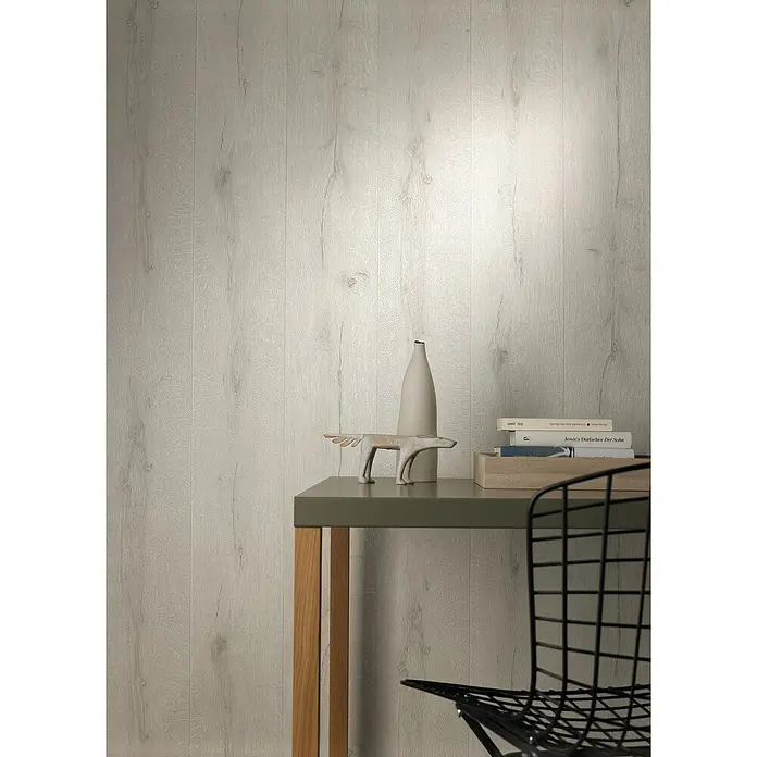 Rasch Vliestapete Holz I - Altweiß, Holzoptik, 10,05 x 0,53 m - Elegantes Interieur mit einem minimalistischen Tisch, dekoriert mit einer Vase, einer Skulptur und Büchern, vor einer dezenten Holzpaneelwand und Stuhl.