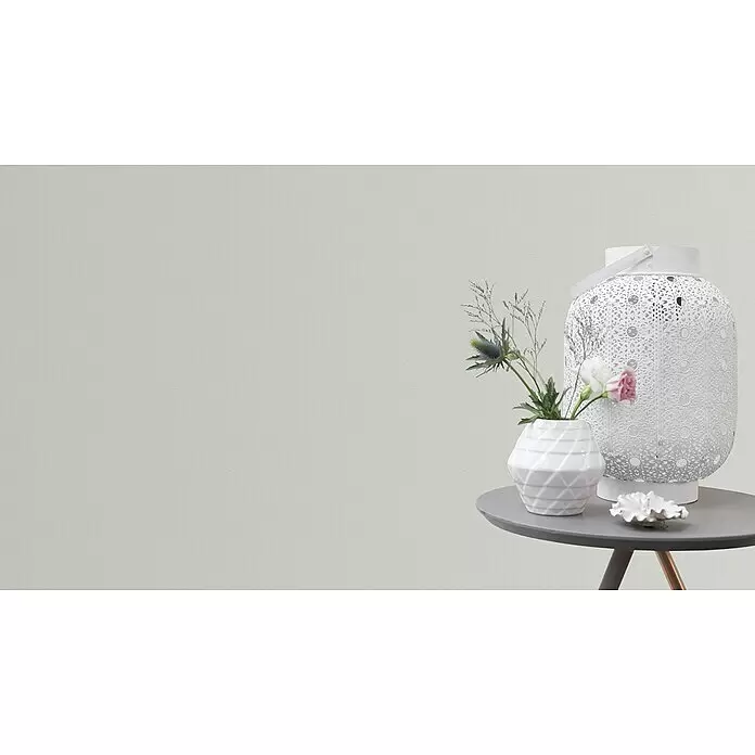Rasch Vliestapete - Weiß, Uni, 10,05 x 0,53 m, Feine Struktur - Dekorative weiße Laterne, Vase mit blauen und rosa Blumen und weißer Muschel auf einem runden grauen Tisch.