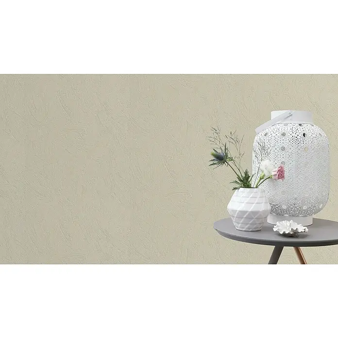 Rasch Vliestapete Putzstruktur - Creme, Uni, 10,05 x 0,53 m, Spachtelstruktur - Nahaufnahme eines dekorativen Tischarrangements mit einer weißen Laterne, einer Vase mit Blumen und einer Muschel auf einem grauen Tisch.