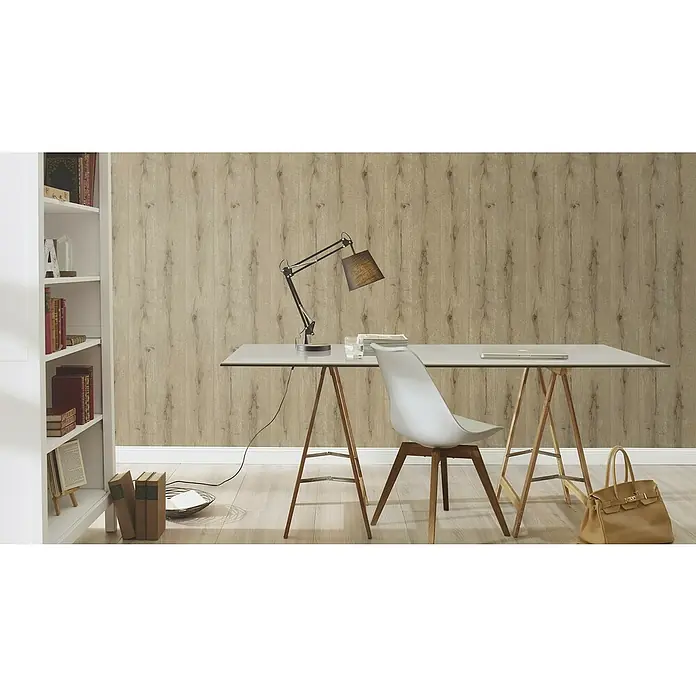 Rasch Vliestapete Holz I - Braun, Holzoptik, 10,05 x 0,53 m - Diese Abbildung zeigt eine Leseecke mit einer Lampe, Büchern und einer hellbraunen Handtasche, die auf dem Boden steht. Das Zimmer ist mit Bücherregalen und einem Tisch ausgestattet.