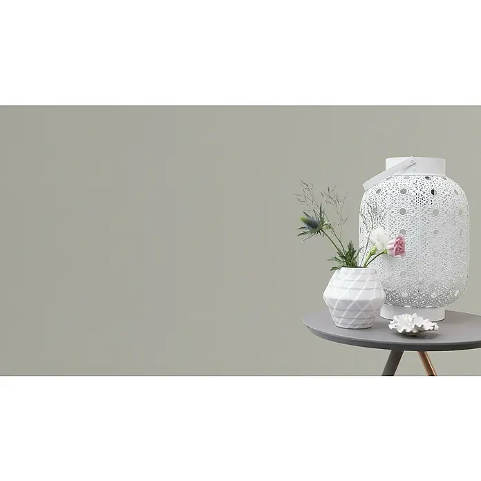 Rasch Vliestapete Flitter - Greige, Uni, 10,05 x 0,53 m - Dekorative weiße Laterne neben einer weißen Vase mit Blumen auf einem grauen Tisch.