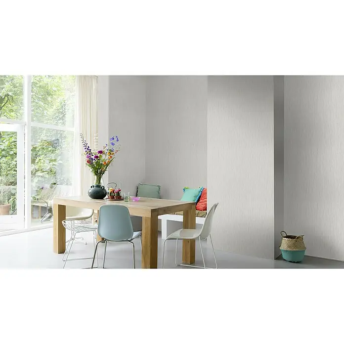 Rasch Rock'n Rolle Vliestapete Linear - Grau, Uni, 10,05 x 0,53 m - Innenaufnahme eines Esszimmers mit Holztisch, Stühlen, Blumen und einem Korb. Die Tapete ist in einem hellen Farbton gehalten.