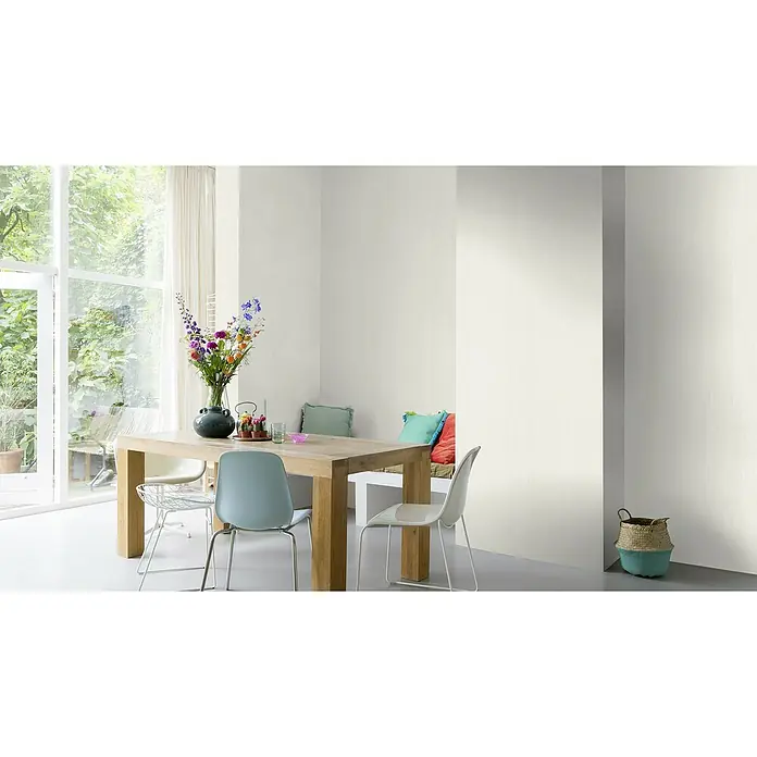 Rasch Rock'n Rolle Vliestapete Linear - Weiß, Uni, 10,05 x 0,53 m - Ein einladender Essbereich mit Holztisch, Stühlen und einem Blumenstrauß in einem lichtdurchfluteten Raum mit großem Fenster und bunten Kissen.