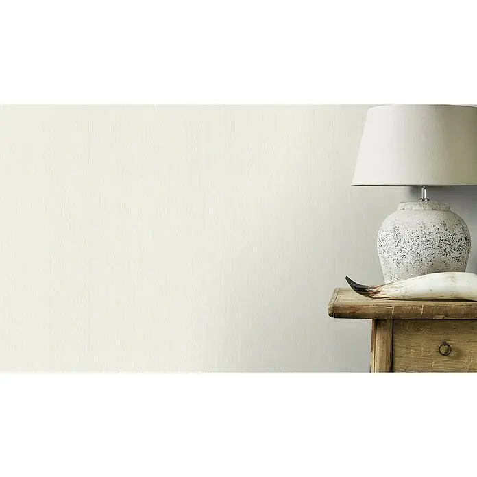 Rasch Rock'n Rolle Vliestapete Linear - Weiß, Uni, 10,05 x 0,53 m - Nahaufnahme eines Nachttisches mit einer Lampe und einem Dekorationsstück, der die elegante Ästhetik des Produkts hervorhebt.