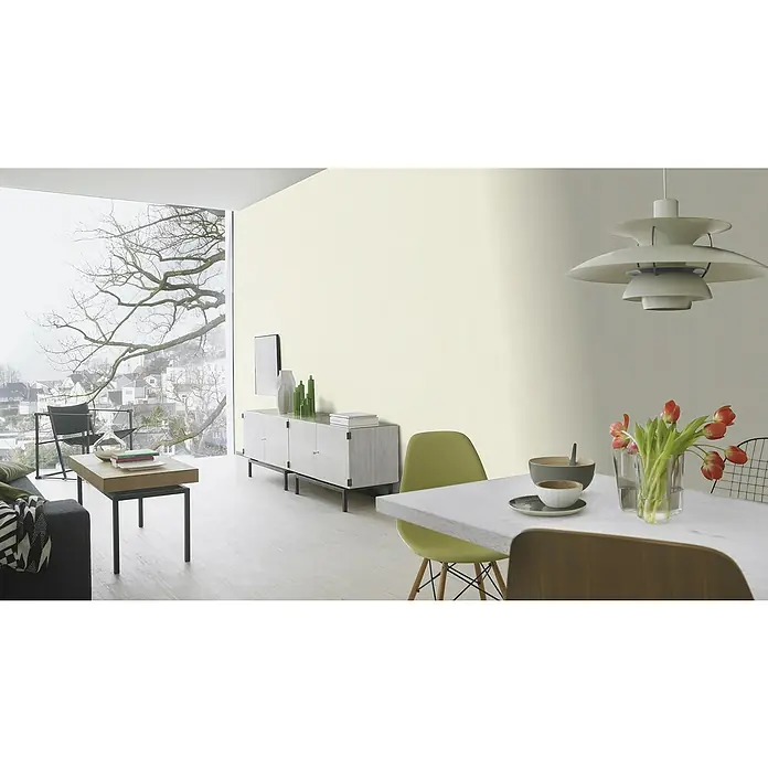 Rasch BARBARA Home Collection II Vliestapete - Hellbeige, Uni, 10,05 x 0,53 m - Ein modernes Wohnzimmer mit einem eleganten Sideboard, stilvollen Möbeln und großen Fenstern, die eine malerische Aussicht bieten.