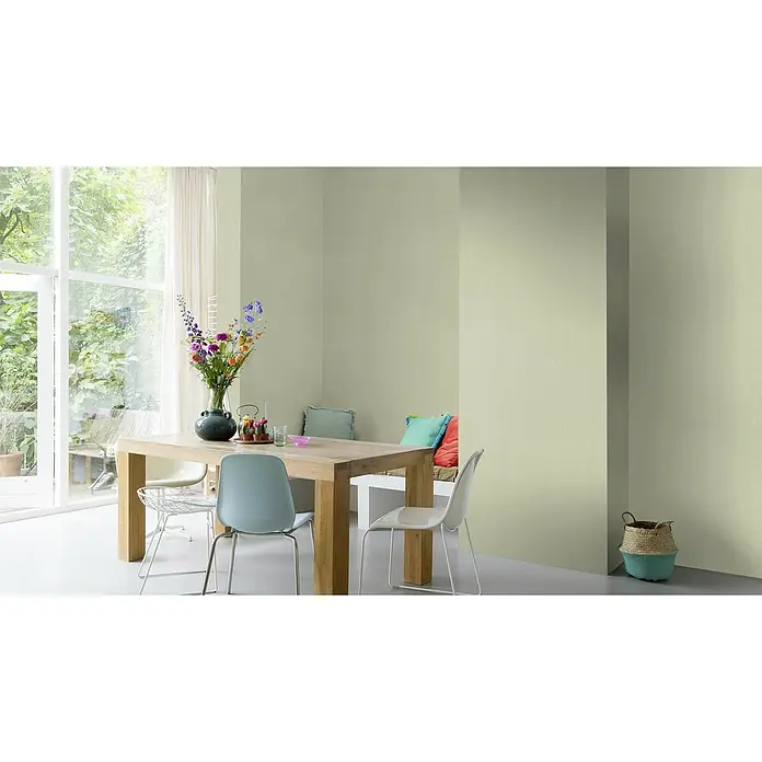 Rasch BARBARA Home Collection II Vliestapete - Pastellgrün, Uni, 10,05 x 0,53 m - Ein helles Esszimmer mit einem Holztisch, Stühlen und Blumen in einer Vase. Der Raum ist in einem sanften Grünton gehalten.