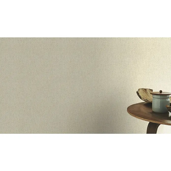 Rasch Poetry II Vliestapete Rusty - Beige, Uni, 10,05 x 0,53 m - Elegantes Stillleben mit einer Holzkiste und einer Schale auf einem Beistelltisch vor einer beigen Wand, das subtile Texturen und neutrale Töne hervorhebt.