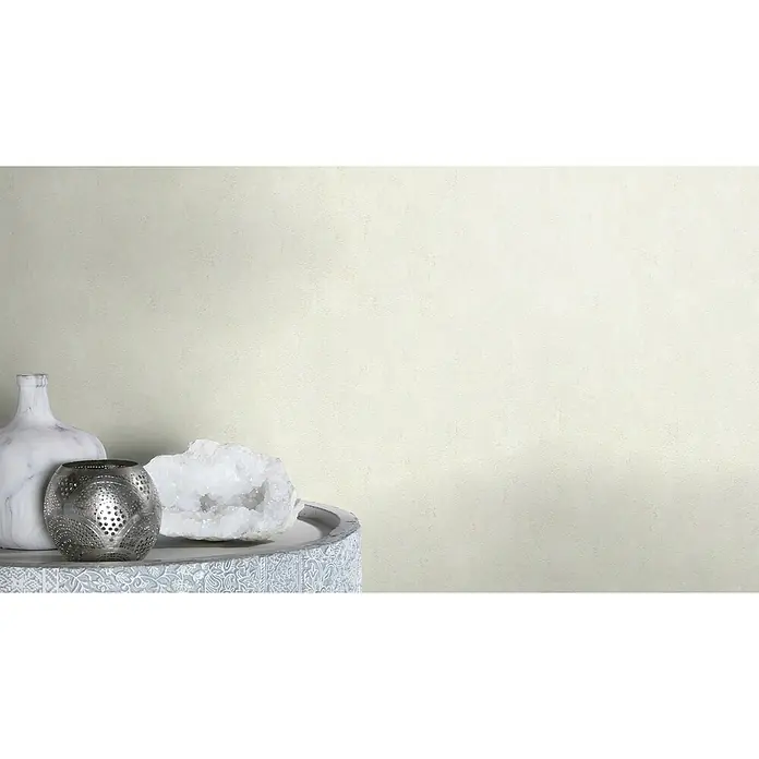 Rasch Vliestapete - Creme, Uni, 10,05 x 0,53 m, Spachtelstruktur - Stillleben mit einer Marmorvase, einem silbernen Teelichthalter und einem Quarzkristall auf einem verzierten Tisch.