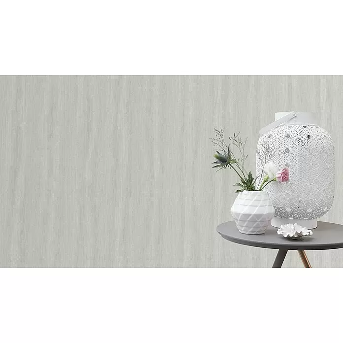 Rasch Vliestapete Längsstreifen - Weiß, Uni, 10,05 x 0,53 m - Hellgraue Tapete mit feinem, dezent strukturiertem Muster, in einem Raum mit Dekotisch und Blumen gezeigt.