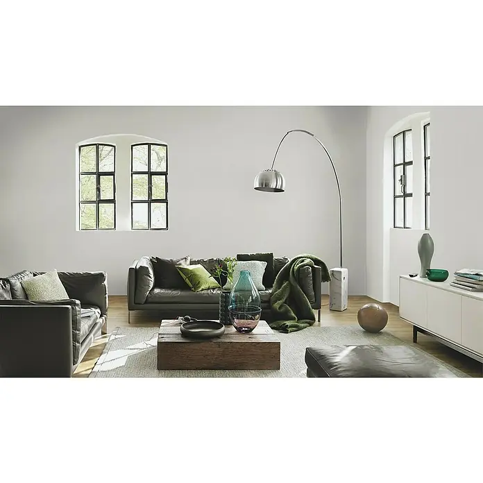 Rasch Vliestapete - Braun/Erdtöne/Taupe, Uni, 10,05 x 0,53 m, Feine Struktur - Ein stilvolles Wohnzimmer mit Ledersofa, Holztisch und moderner Stehlampe. Das Zimmer wird durch Fenster mit Tageslicht erhellt.