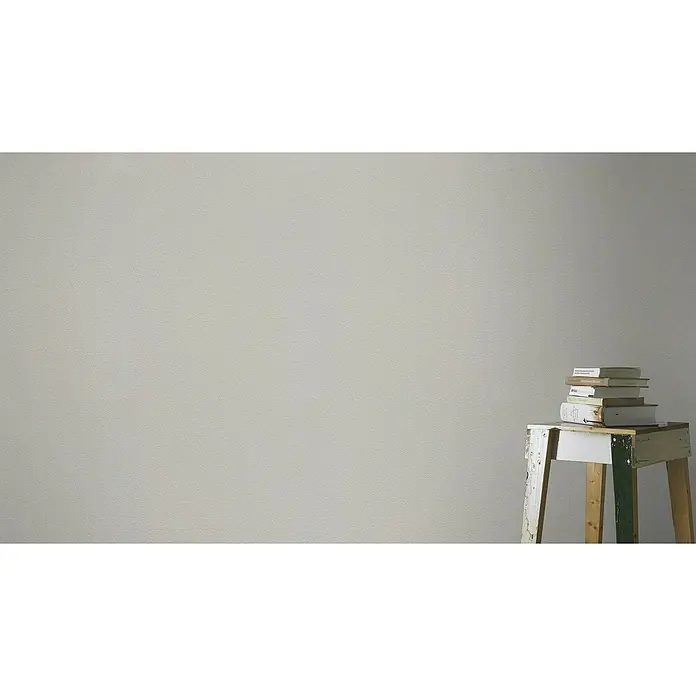 Rasch Vliestapete - Braun/Erdtöne/Taupe, Uni, 10,05 x 0,53 m, Feine Struktur - Ein Stapel Bücher liegt auf einem rustikalen Holzschemel vor einer schlichten Wand. Bücher in verschiedenen Größen und Farben sind zu sehen.