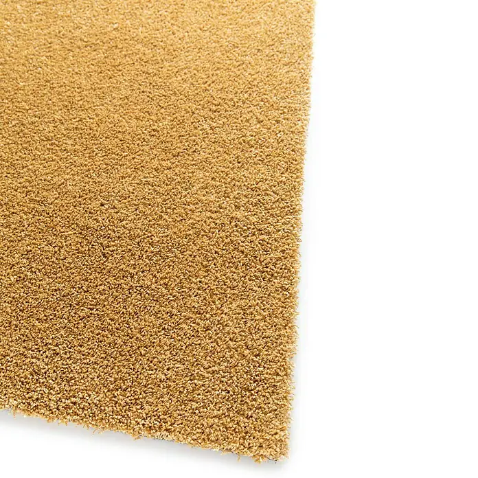 Alfombra de pelo corto Tender - Mostaza, 230 x 160 cm - Primer plano de una alfombra beige con una textura densa, perfecta para crear un ambiente cálido y acogedor en cualquier habitación.
