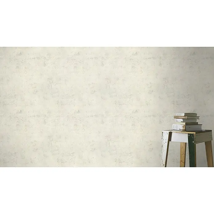 Rasch Vliestapete Beton - Weiß, Betonoptik, 10,05 x 0,53 m - Ein Stapel Bücher ruht auf einem rustikalen, weiß gestrichenen Hocker vor einer schlichten Wand. Perfekt für entspannte Lesestunden.