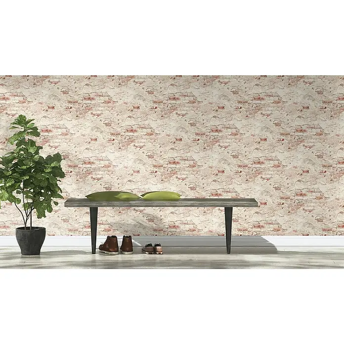Rasch Vliestapete Bruchstein - Rot/Beige/Weiß, Steinoptik, 10,05 x 0,53 m - Das Bild zeigt eine Zimmerpflanze im Topf neben einer Sitzbank mit Kissen und Schuhen vor einer Ziegelwand. Die Szene wirkt einladend und gemütlich.