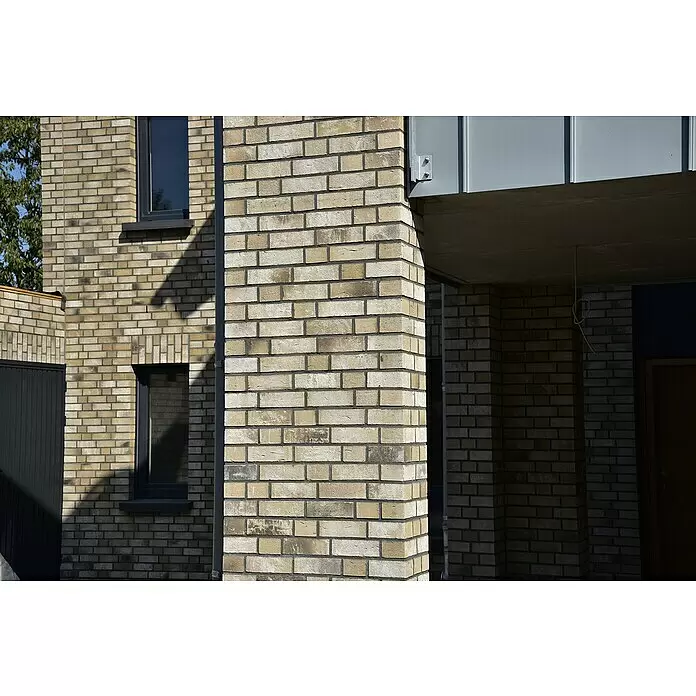 Celina Klinker Verblendstein-Ecke Handstrich Valencia - 21,5 x 6,5 x 10,25 cm, Beige, Steinoptik - Moderne Gebäudefassade mit hellbeigem und grauem Mauerwerk, dunklen Fenstern und grauen Metallpaneelen.