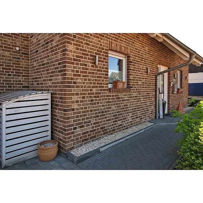 Celina Klinker Verblendstein Montana Ravenna - 6,5 x 21,5 cm, Braun, Steinoptik - Ein schönes Haus mit Backsteinfassade und weißem Schuppen. Ein dekorativer Blumentopf rundet das Erscheinungsbild ab.