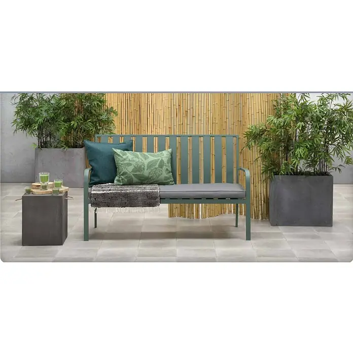 Banco de jardín Bruno - An x Pr x Al: 150 x 68 x 90 cm, Verde - Banco de jardín verde con cojines y manta delante de un fondo de bambú, flanqueado por maceteros, con una mesa auxiliar con bebidas.
