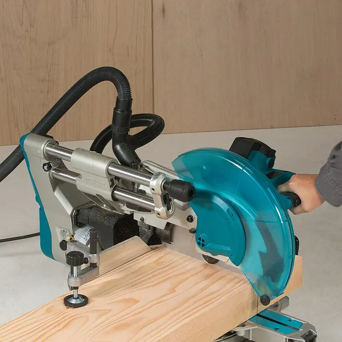 Makita Kapp- & Gehrungssäge LS1219L - 1.800 W, Durchmesser Sägeblatt: 305 mm, Leerlaufdrehzahl: 0 U/min - 3.200 U/min - Nahaufnahme einer Makita-Kapp- und Gehrungssäge beim Schneiden eines Holzstücks.