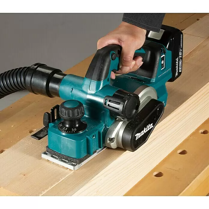 Makita LXT 18V Akku-Hobel - 18 V, Ohne Akku, Leerlaufdrehzahl: 12.000 U/min - Eine Person bedient einen türkis-schwarzen Makita Akku-Hobel auf einem Holzbrett, mit Staubschlauch und Tiefenverstellung.