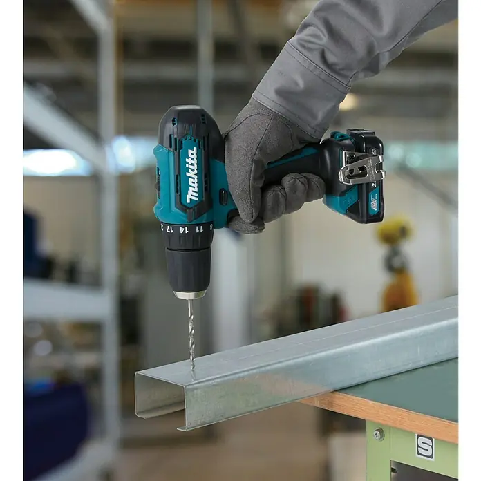 Makita CXT 12V max. Akku-Bohrschrauber DF333DZ - 12 V, Ohne Akku - Eine Makita Akku-Bohrmaschine beim Bohren in ein Metallstück. Die Maschine liegt gut in der Hand und ist ideal für Heimwerkerarbeiten.