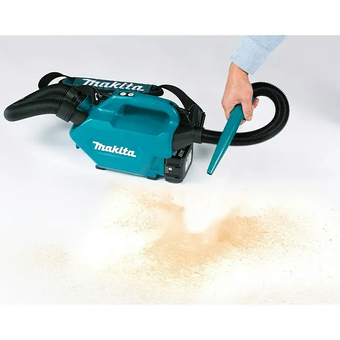 Makita LXT 18V Akku-Staubsauger DCL184Z - 18 V, Ohne Akku, Behältervolumen: 0,5 l - Makita Akku-Staubsauger im Einsatz. Der leichte Staubsauger saugt Staubpartikel von einem weißen Untergrund. Hand führt den Staubsauger.