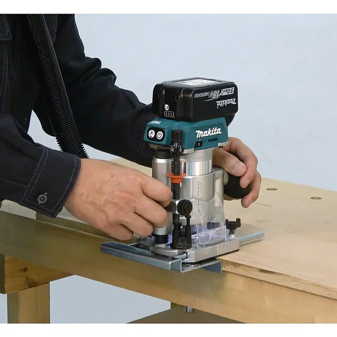 Makita LXT 18V Akku-Multifunktionsfräse DRT50ZJX2 - 18 V, Ohne Akku, Leerlaufdrehzahl: 10.000 U/min - 30.000 U/min - Der Makita Akku-Trimmer wird auf einer Holzoberfläche bedient, wobei die Hände die Einstellungen anpassen. Ein Werkzeug für präzise Holzarbeiten.