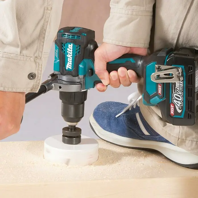 Makita XGT 40V max. Taladro atornillador de batería DF001GZ - 40 V, Sin batería - Primer plano de un taladro Makita en acción, perforando un agujero en una tabla de madera. La herramienta muestra potencia y perforación de precisión.