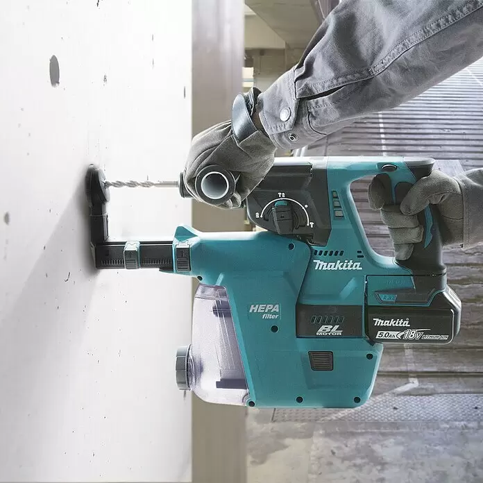 Makita LXT 18V Martillo combinado de batería DHR243RTJ - 18 V, 2 baterías, 5 Ah, 2 J, Con extracción de polvo - Taladro percutor Makita turquesa con extractor de polvo, utilizado por manos enguantadas en una pared clara.