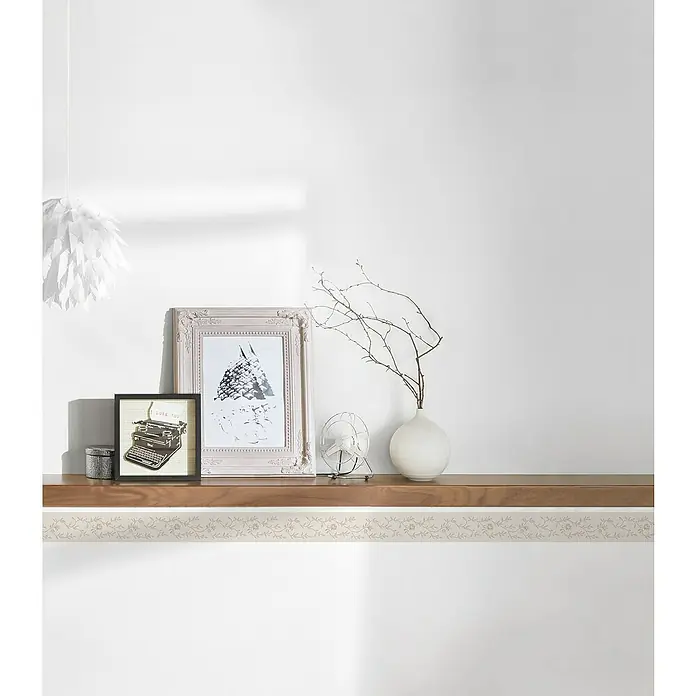A.S. Création Only Borders 11 Tapetenborte Blumenranke - Kunststoff, Gold - Einrichtungselemente auf einem Holzregal: gerahmte Bilder, eine Vintage-Schreibmaschine, eine Vase mit Zweigen und eine dekorative Windmühle.