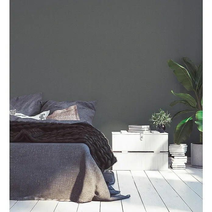A.S. Création Desert Lodge Vliestapete - Eisengrau, Uni, 10,05 x 0,53 m - Ein gemütliches Schlafzimmer mit einem großen Bett und einem weißen Nachttisch, dekoriert mit Pflanzen und Büchern. Elegantes Schlafzimmer-Design.