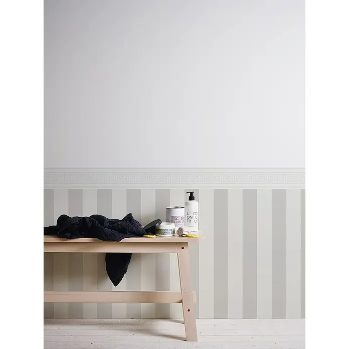 A.S. Création Only Borders 11 Tapetenborte Mäander - Weiß, 5 x 0,13 m, Selbstklebefolie - Eine hölzerne Ablage mit Badutensilien, Handtuch und Zitronenscheiben vor einer gestreiften Wand mit Bordüre.