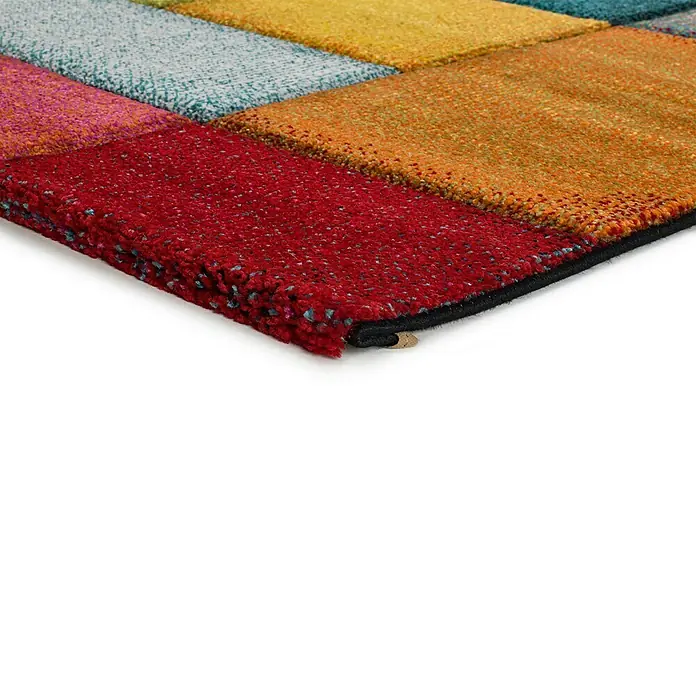 Alfombra de pelo corto Harlequín - Multicolor, 230 x 160 cm - Vista detallada de una colorida alfombra con diseños cuadrados en rojo, naranja, amarillo, azul y rosa, resaltando su textura.