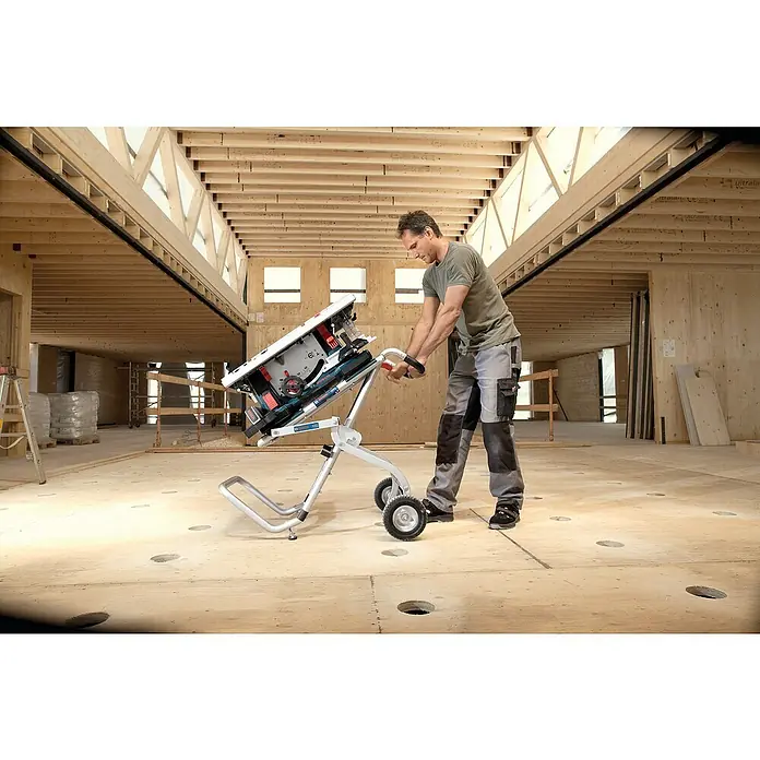 Bosch Professional Tischkreissäge GTS 10 XC - 2.000 W, Durchmesser Sägeblatt: 254 mm, Schnitttiefe bei 90 °: 79 mm - Mann transportiert eine Bosch GTS 635-216 Professional Tischkreissäge auf einem GTA 6000 Untergestell in einem Rohbau.