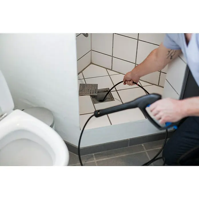 Nilfisk Rohrreinigungs-Set - 15 m, Passend für: Nilfisk Hochdruckreiniger - Ein Installateur benutzt eine Rohrreinigungsmaschine, um einen verstopften Duschabfluss zu reinigen. Das Werkzeug wird benutzt, um Ablagerungen zu beseitigen.