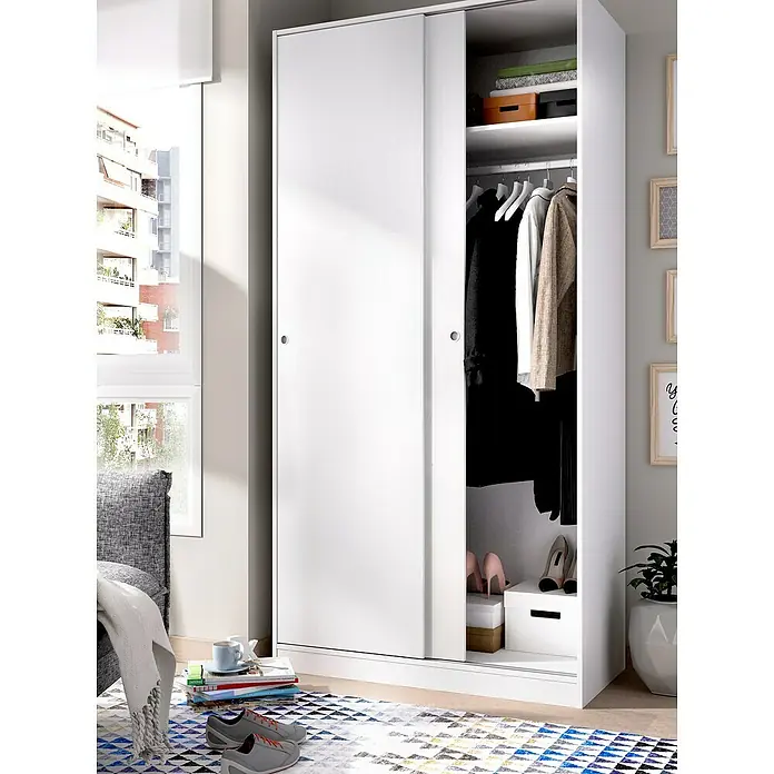 Dekit Armario de puertas correderas Slide Plus - L x An x Al: 50 x 100 x 204 cm, Blanco - Un armario blanco con puertas correderas se encuentra en un dormitorio, ofreciendo amplio espacio de almacenamiento para ropa y accesorios.