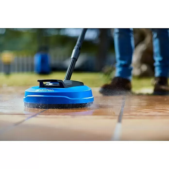Nilfisk Limpiadora de superficies Power Patio - Específico para: Limpiadoras de alta presión Nilfisk - Limpiador azul Nilfisk Power Patio rociando agua en una terraza de madera, usado por una persona.