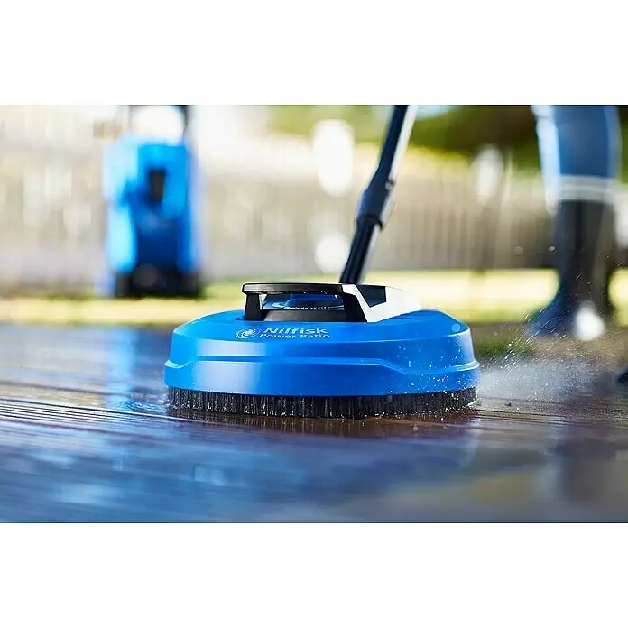 Nilfisk Limpiadora de superficies Power Patio - Específico para: Limpiadoras de alta presión Nilfisk - Limpiador Nilfisk Power Patio azul y negro con mango, limpiando activamente una cubierta de madera mojada con salpicaduras de agua.