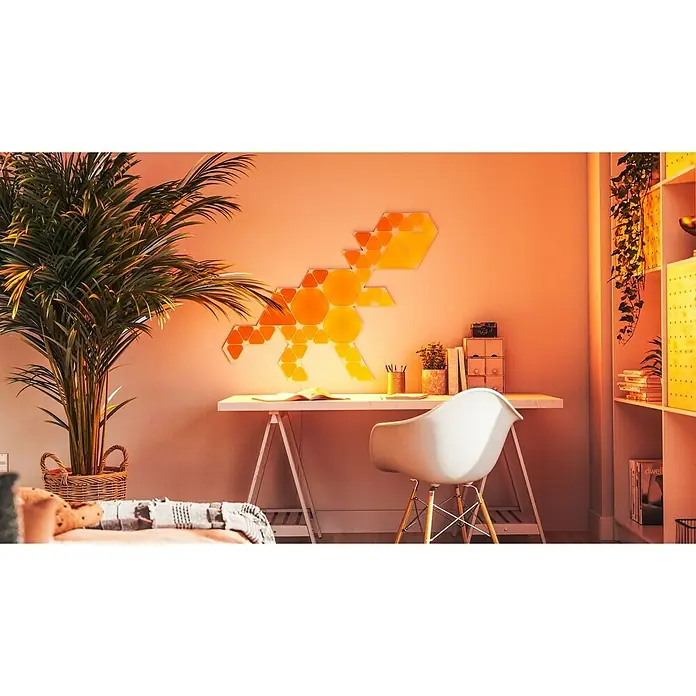 Nanoleaf Starterkit Shapes Triangles 15 Panels - 15 Stk., Weiß, RGBW, Triangles, Smart Home-fähig: Ja - Dinosaurierförmige LED-Wandleuchte in warmen Farben über einem Schreibtisch, die eine gemütliche Atmosphäre schafft.