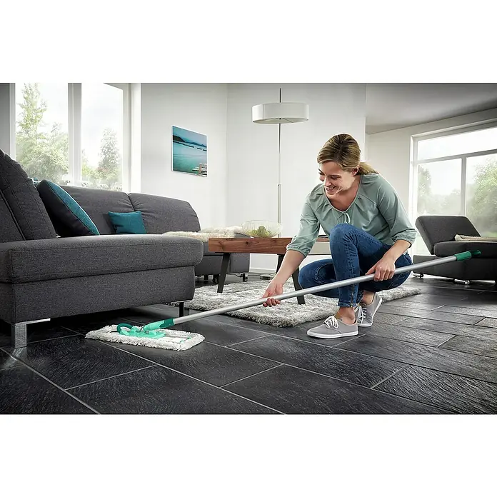 Leifheit Ersatz-Bezug Profi XL Cotton Plus - Blau/Weiß, Passend für: Leifheit Bodenwischer Profi XL - Frau wischt mit einem Bodenwischer eine dunkle Steinfliese im Wohnzimmer. Der Bodenwischer mit seinem silbernen Stiel ist gut sichtbar.